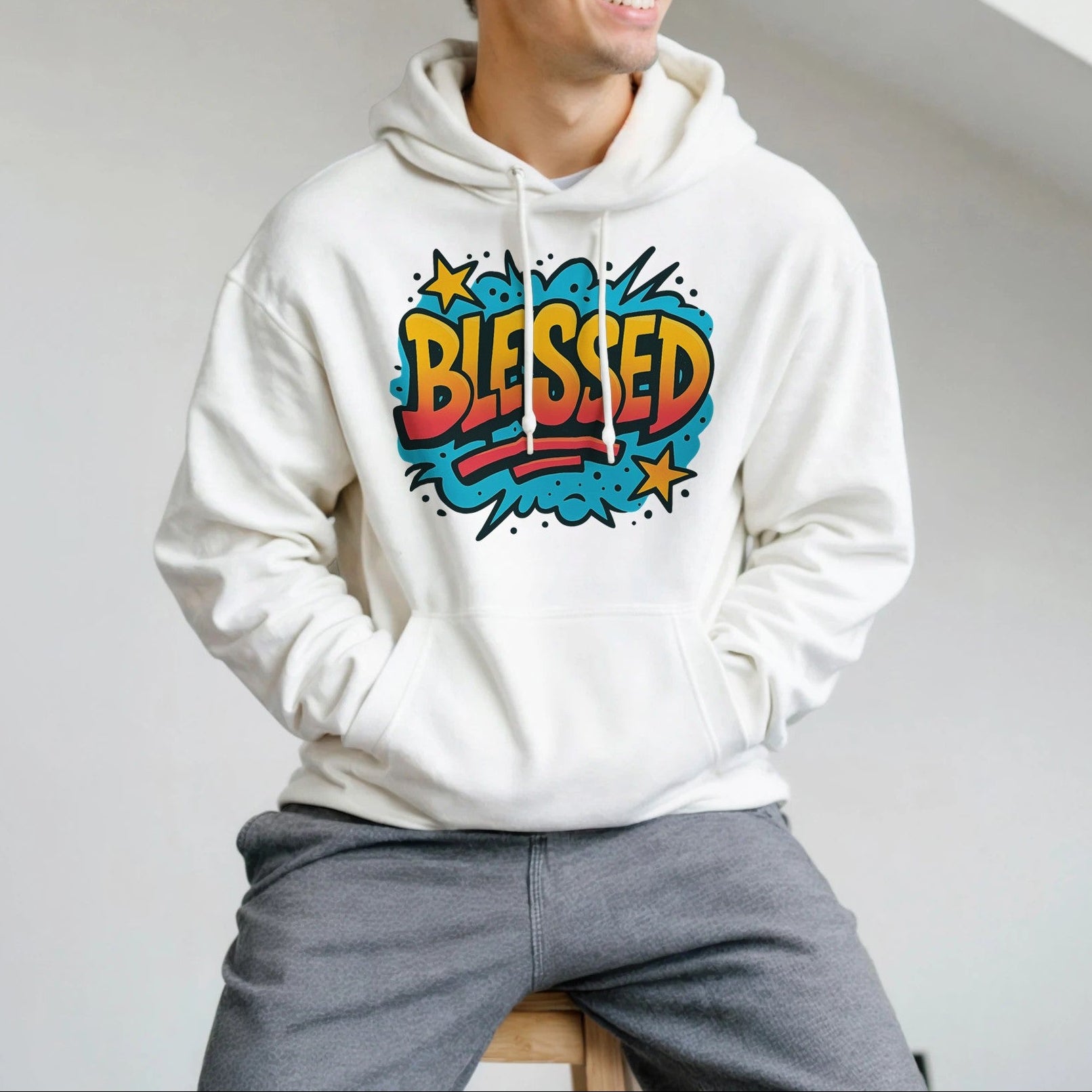Person wearing a white hoodie with 'Blessed' design, sitting indoors.