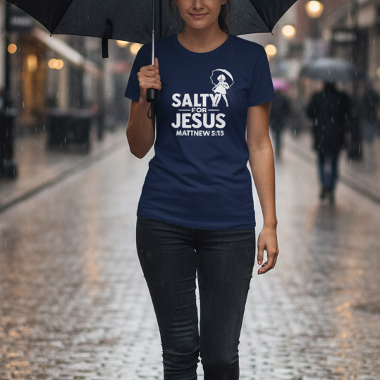 Person holding an umbrella on a rainy city street wearing a blue t-shirt with text.