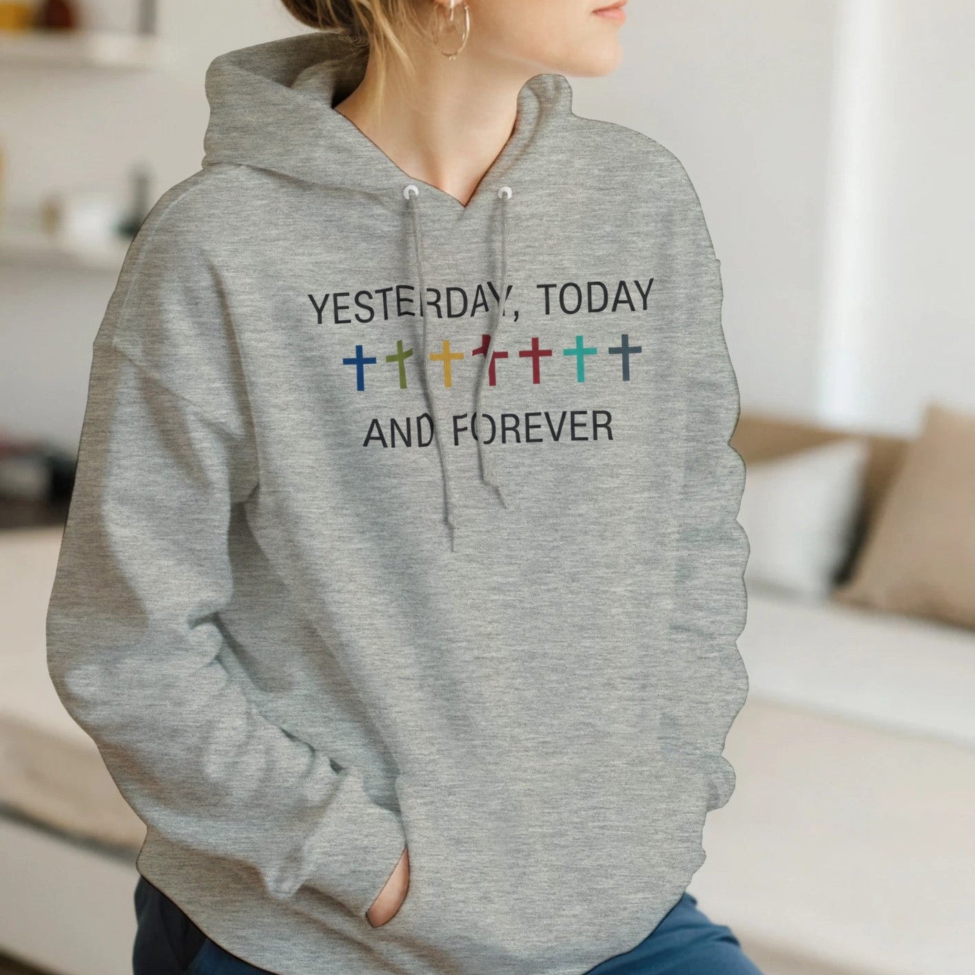 Person wearing a gray hoodie with colorful text in a living room