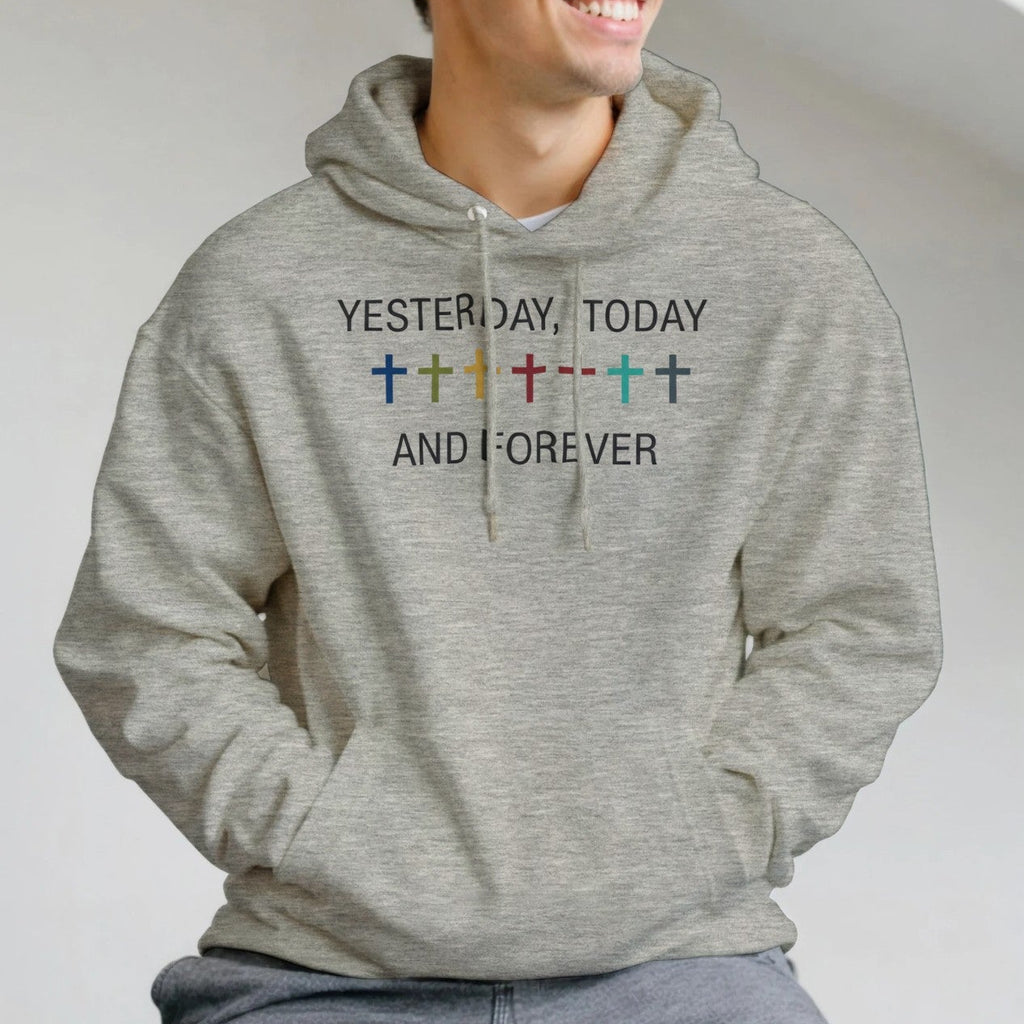 Man wearing a gray hoodie with text and symbols, sitting indoors.