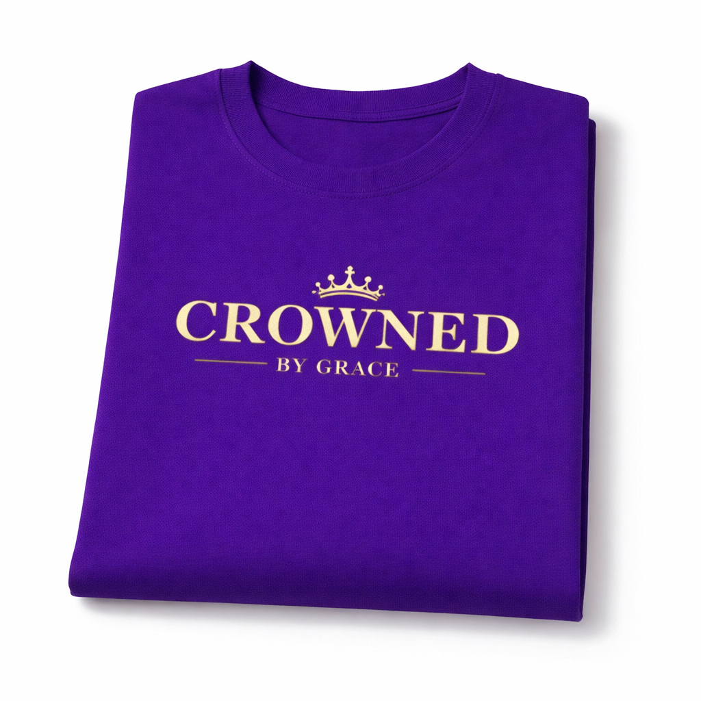 Folded purple t-shirt with 'Crowned by Grace' text on a white background