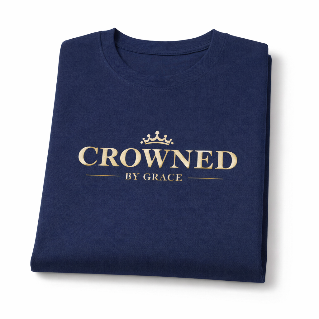 Folded navy blue t-shirt with 'Crowned by Grace' text on a white background
