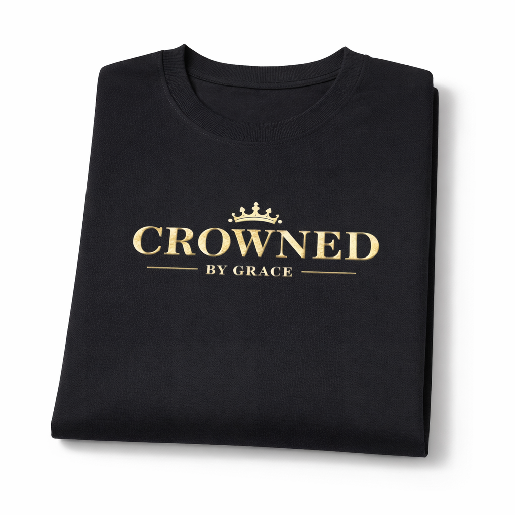 Folded black t-shirt with 'Crowned by Grace' text on a white background