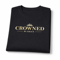 Folded black t-shirt with 'Crowned by Grace' text on a white background