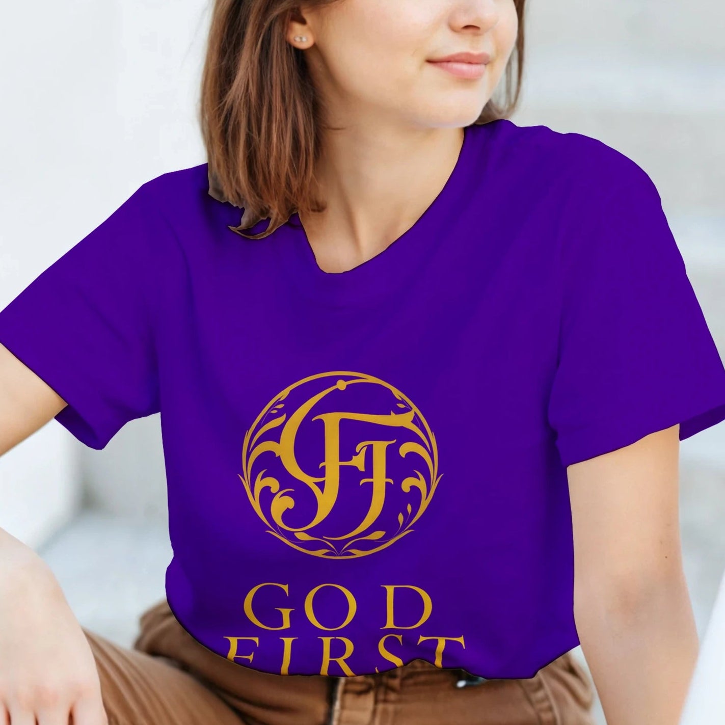Woman wearing a purple t-shirt with gold design and text, sitting on steps.