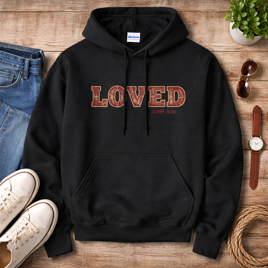Black hoodie with 'LOVED' text on a wooden surface with casual items.