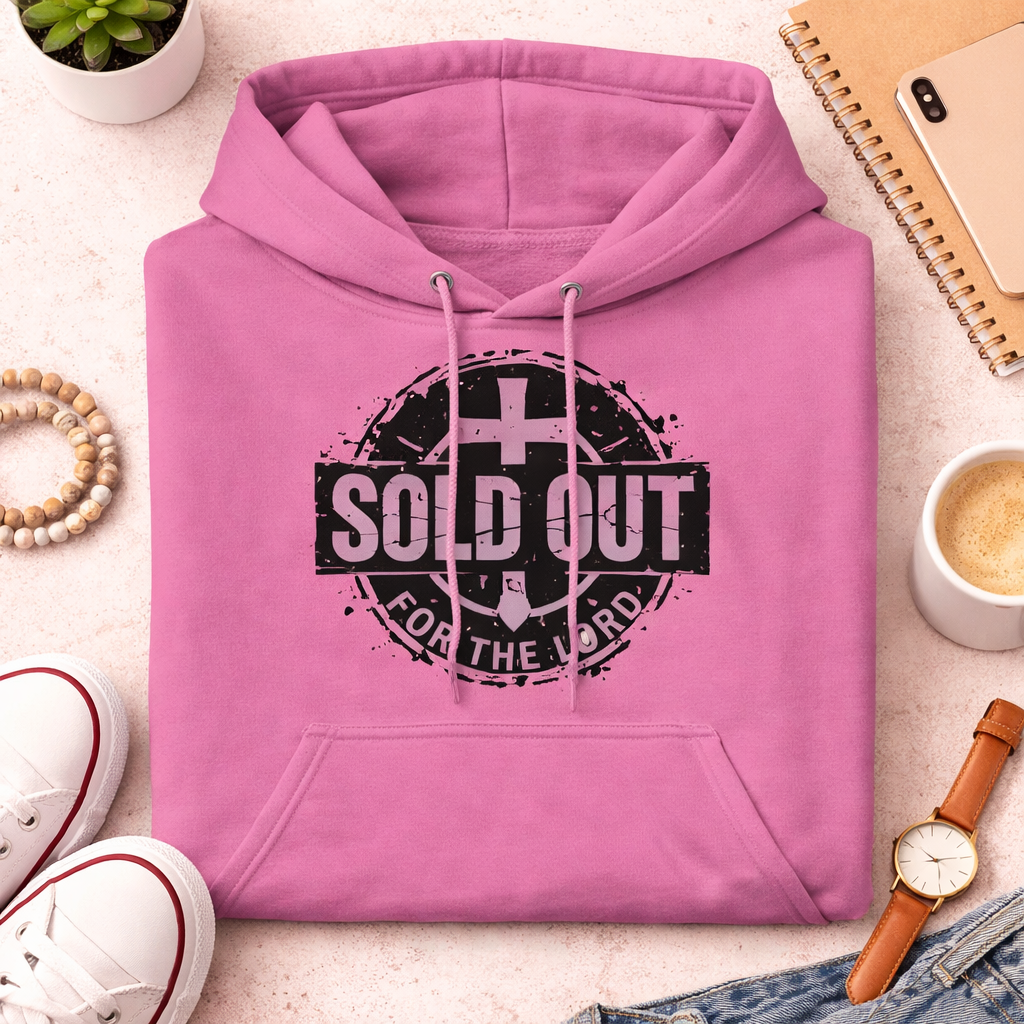 Pink hoodie with 'SOLD OUT FOR THE LORD' text on a light surface with accessories.