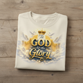 Folded Beige t-shirt with 'To God be the Glory' design on a wooden surface