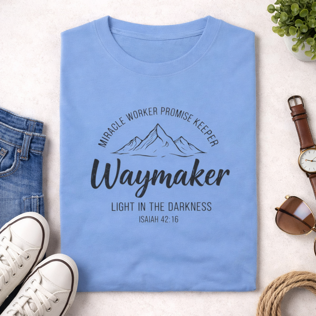 Blue t-shirt with motivational text and mountain graphic on a light surface with accessories.
